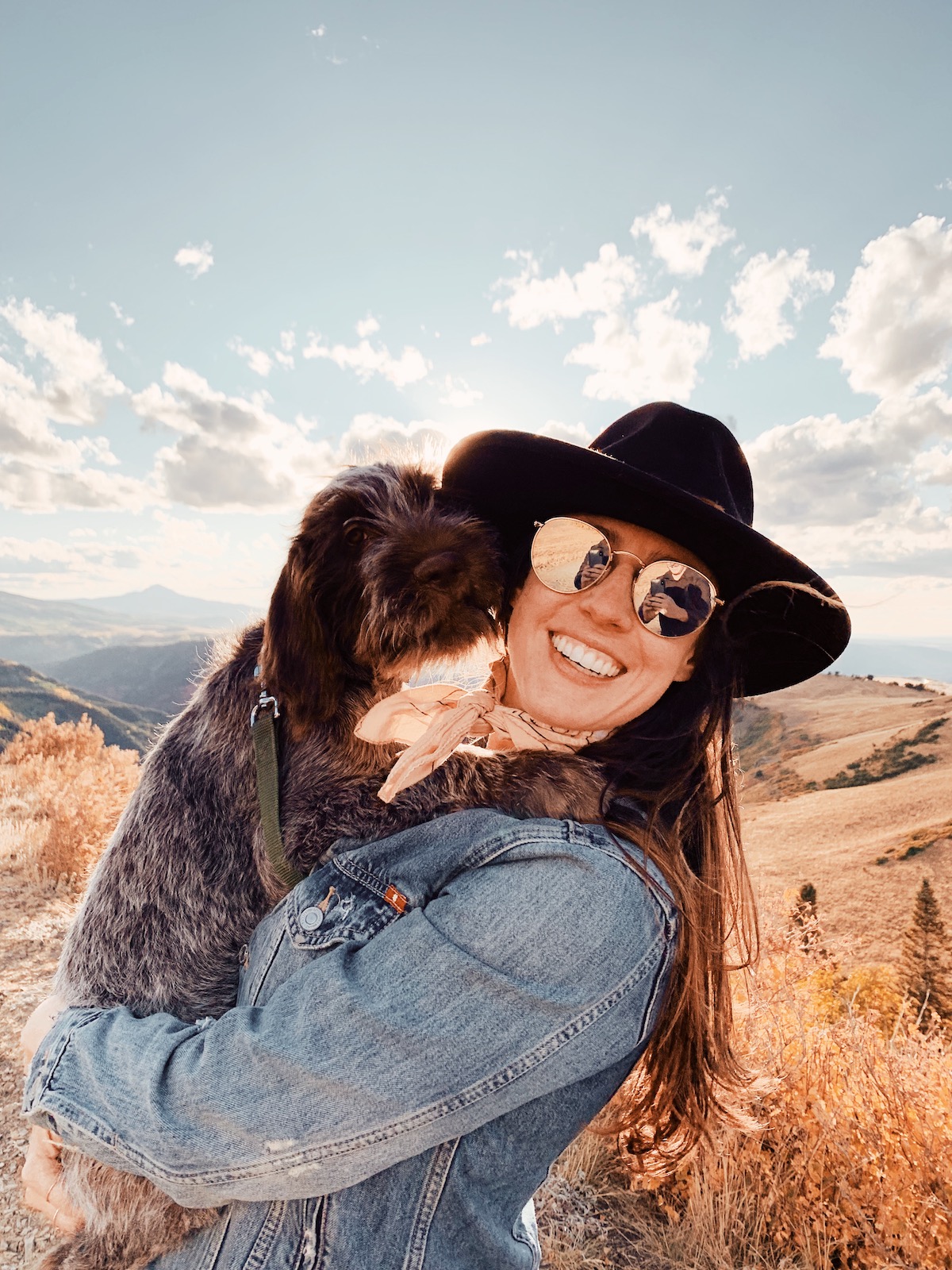 Photo of woman holding dog in a mountainous setting