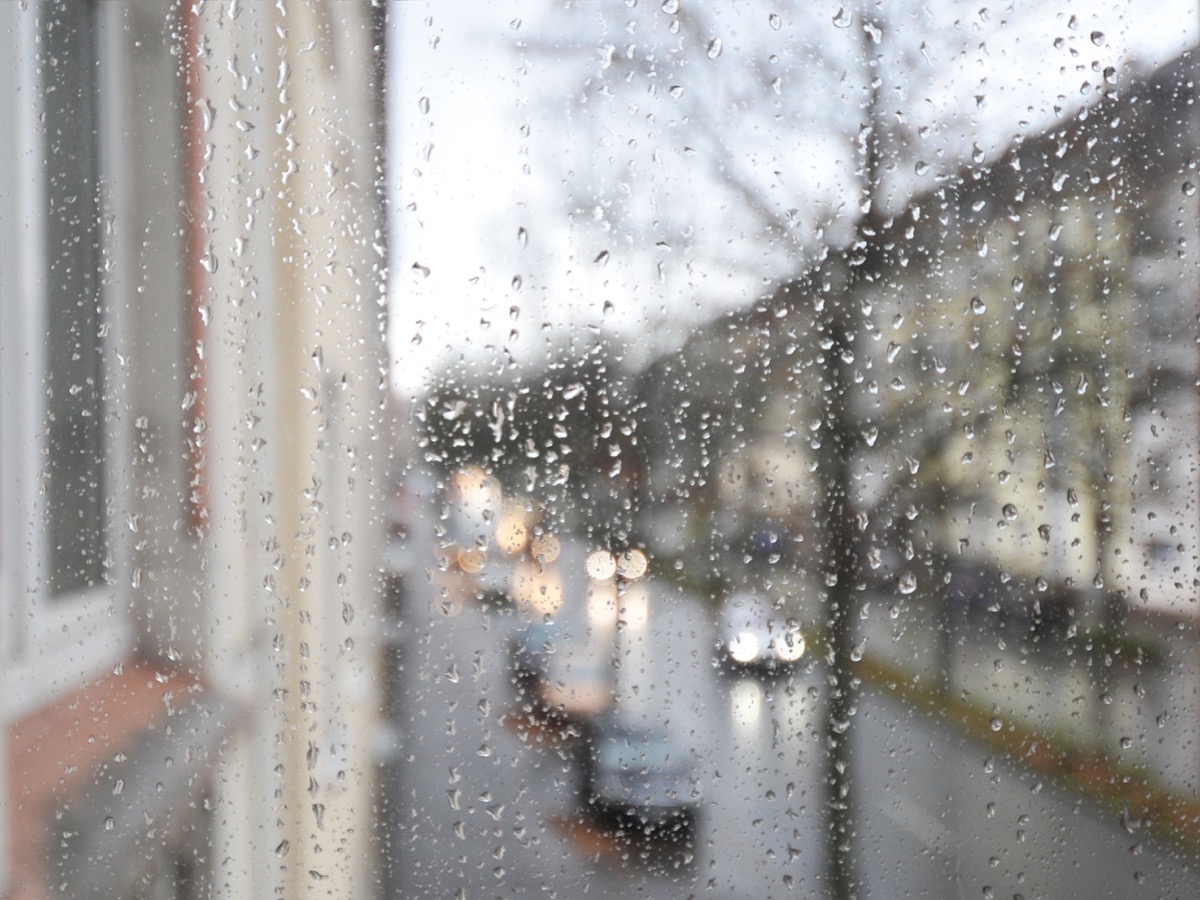 photo city street through water droplets on rainy window