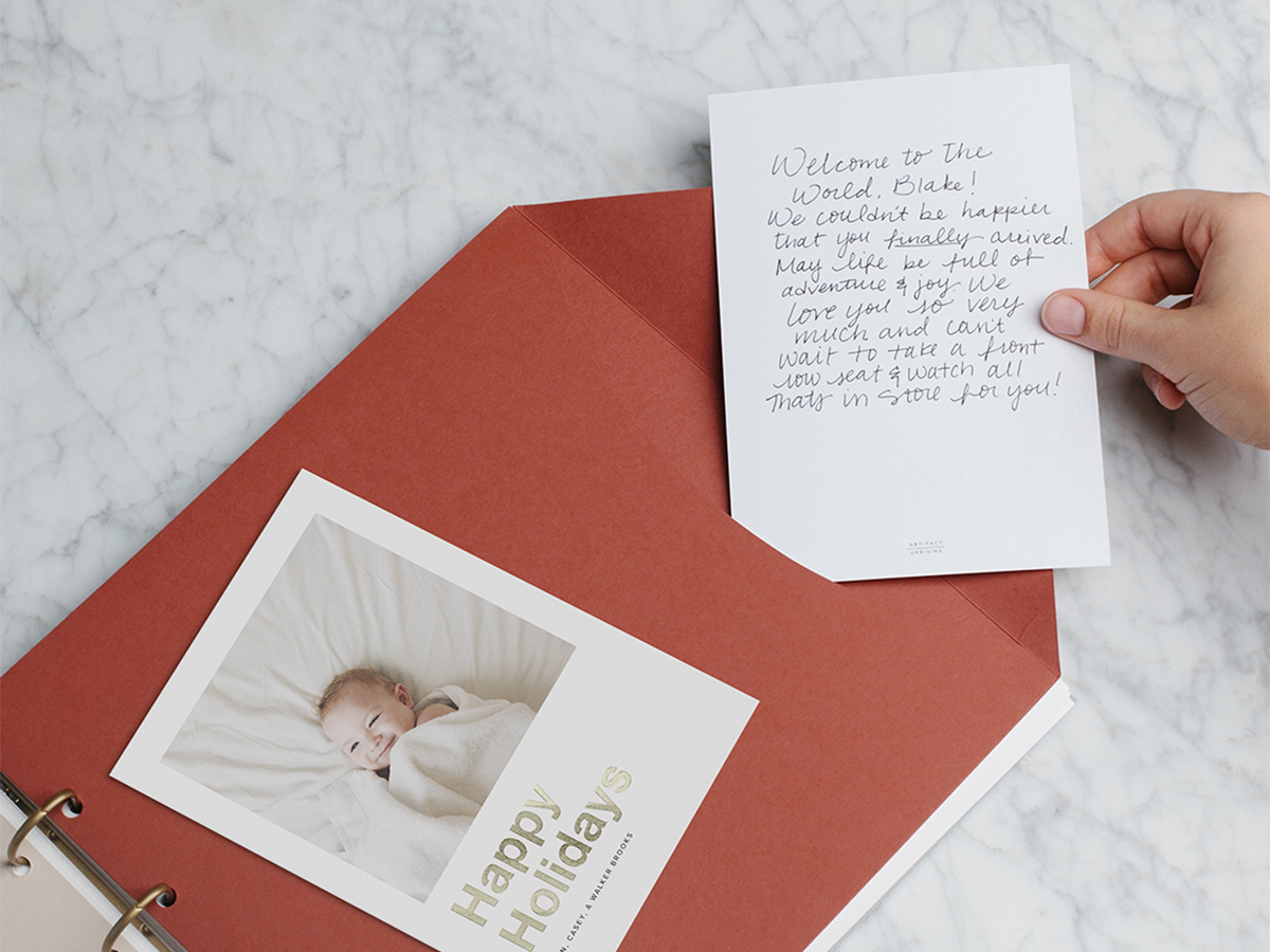 Hand slipping letter to baby into an envelope in a baby book