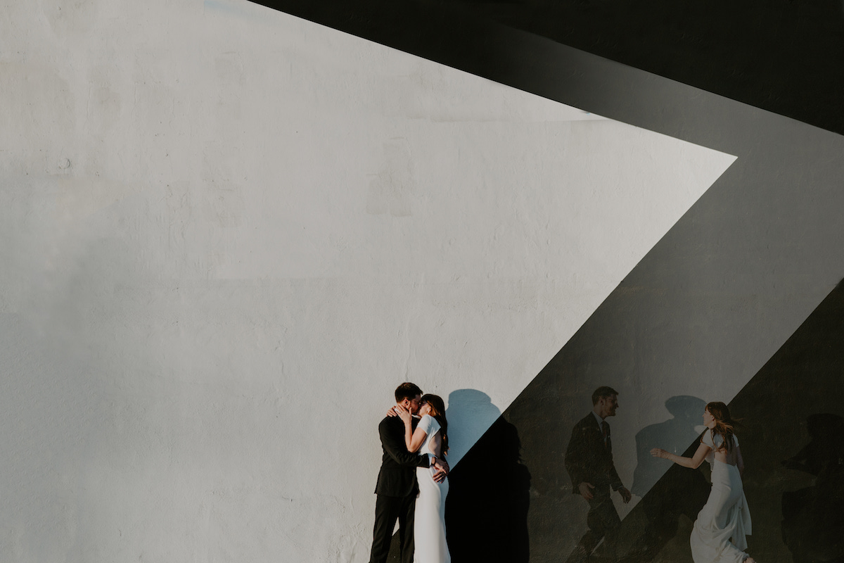 Photo of bride and groom kissing in front of artistic backdrop