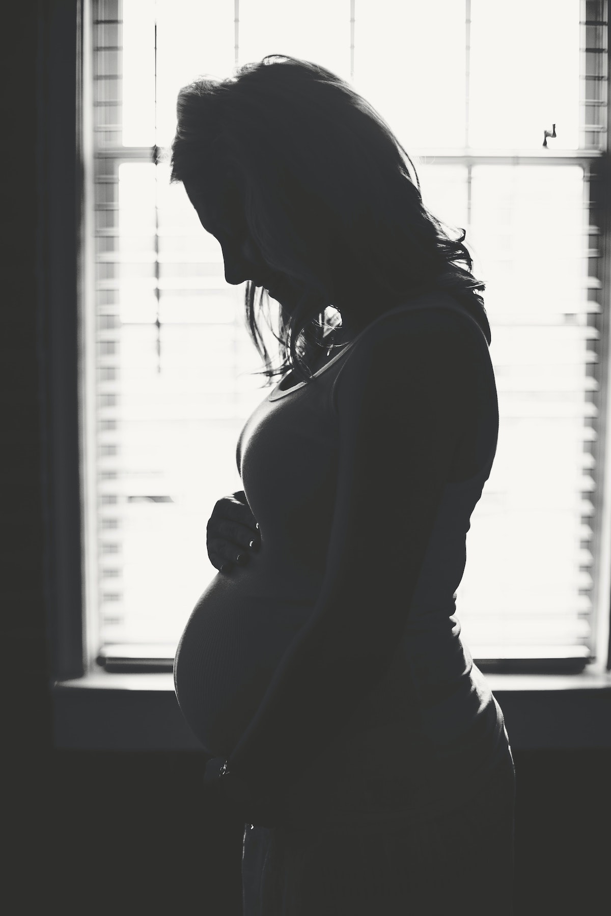 Silhouette of pregnant mother-to-be in front of brightly lit window