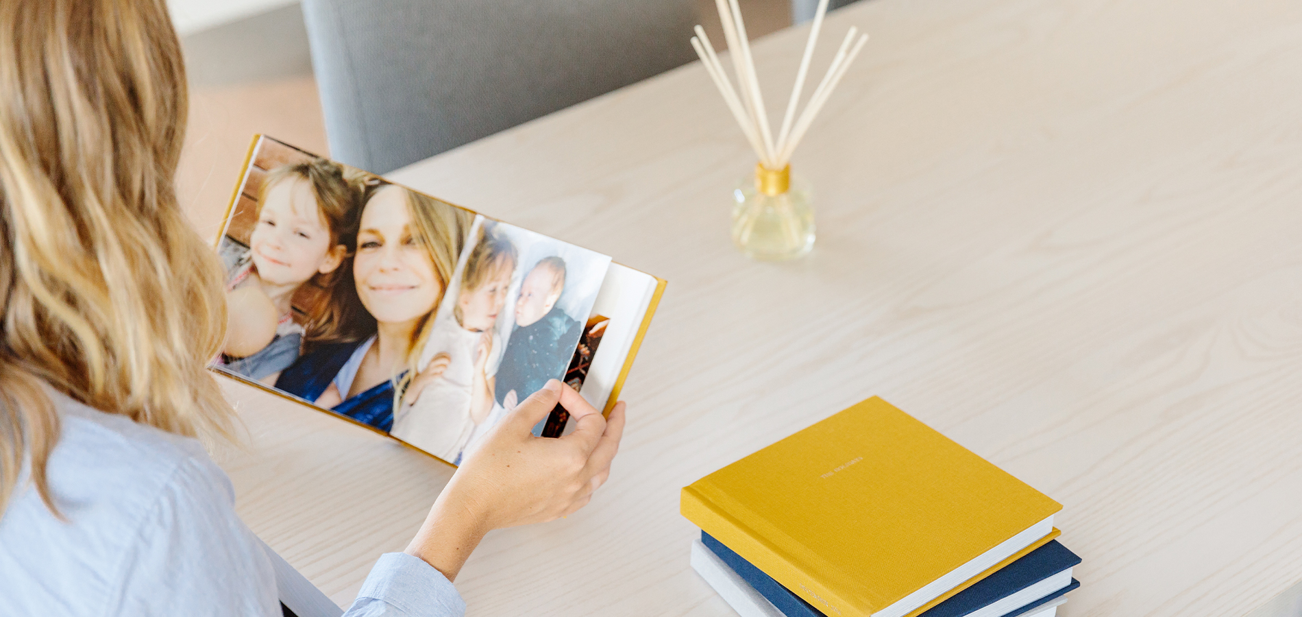 Woman at table flipping through Everyday Photo Book filled with kids' photos