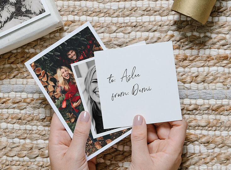 Hand holding photo prints to use as gift tags on wrapped presents